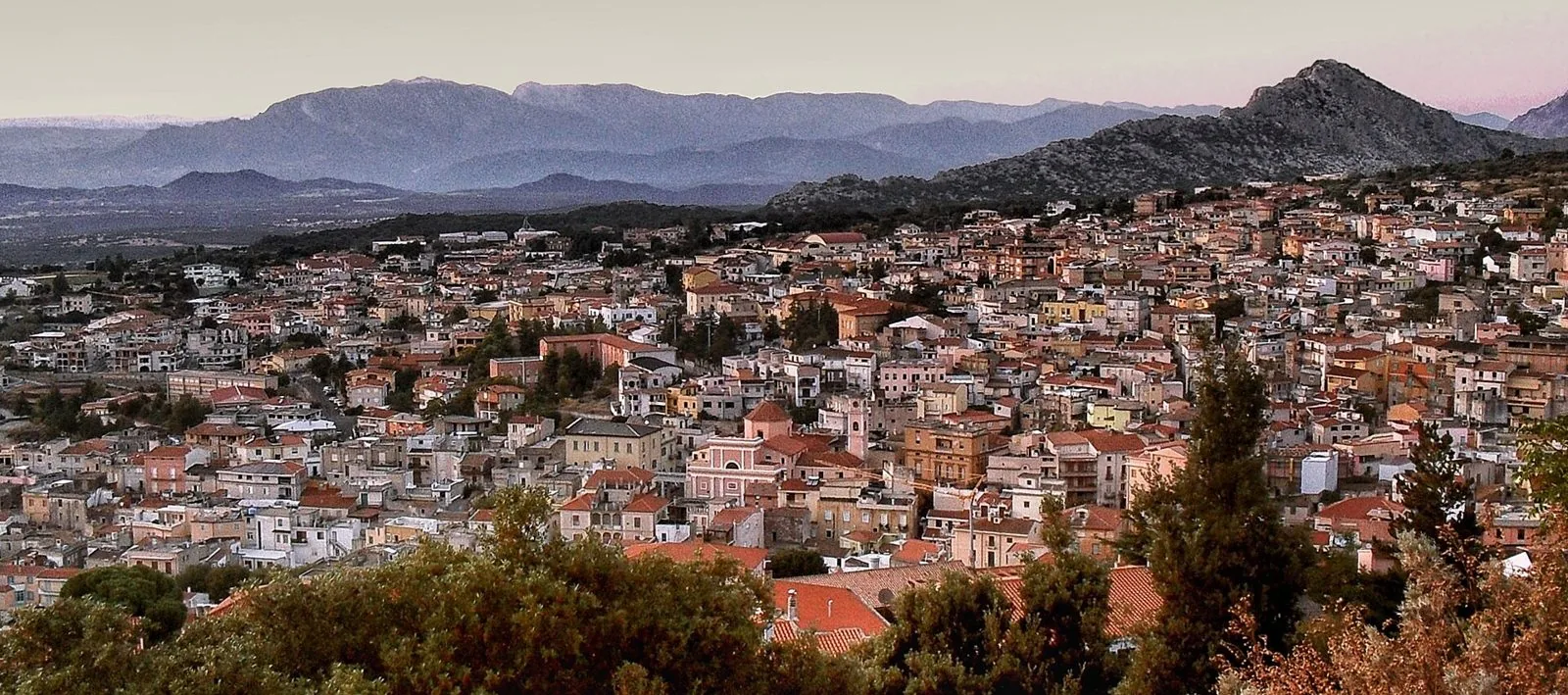 Panorama di Dorgali visto dall'alto al tramonto, con le case del paese e le montagne del Supramonte sullo sfondo