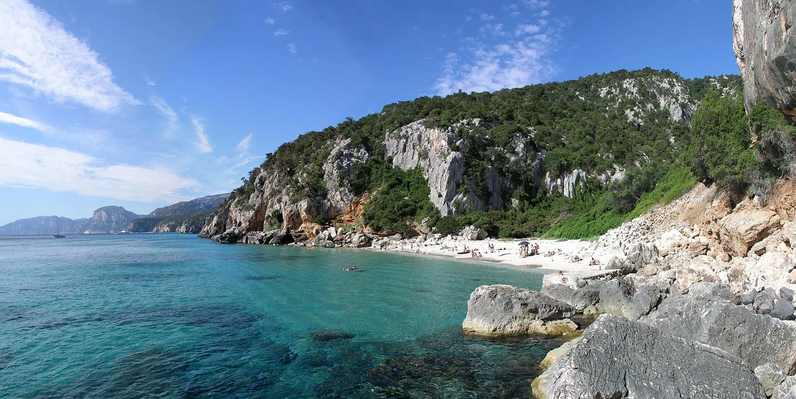 Cala Fuili, piccola spiaggia chiara tra pareti calcaree e macchia mediterranea, con l'acqua turchese in primo piano